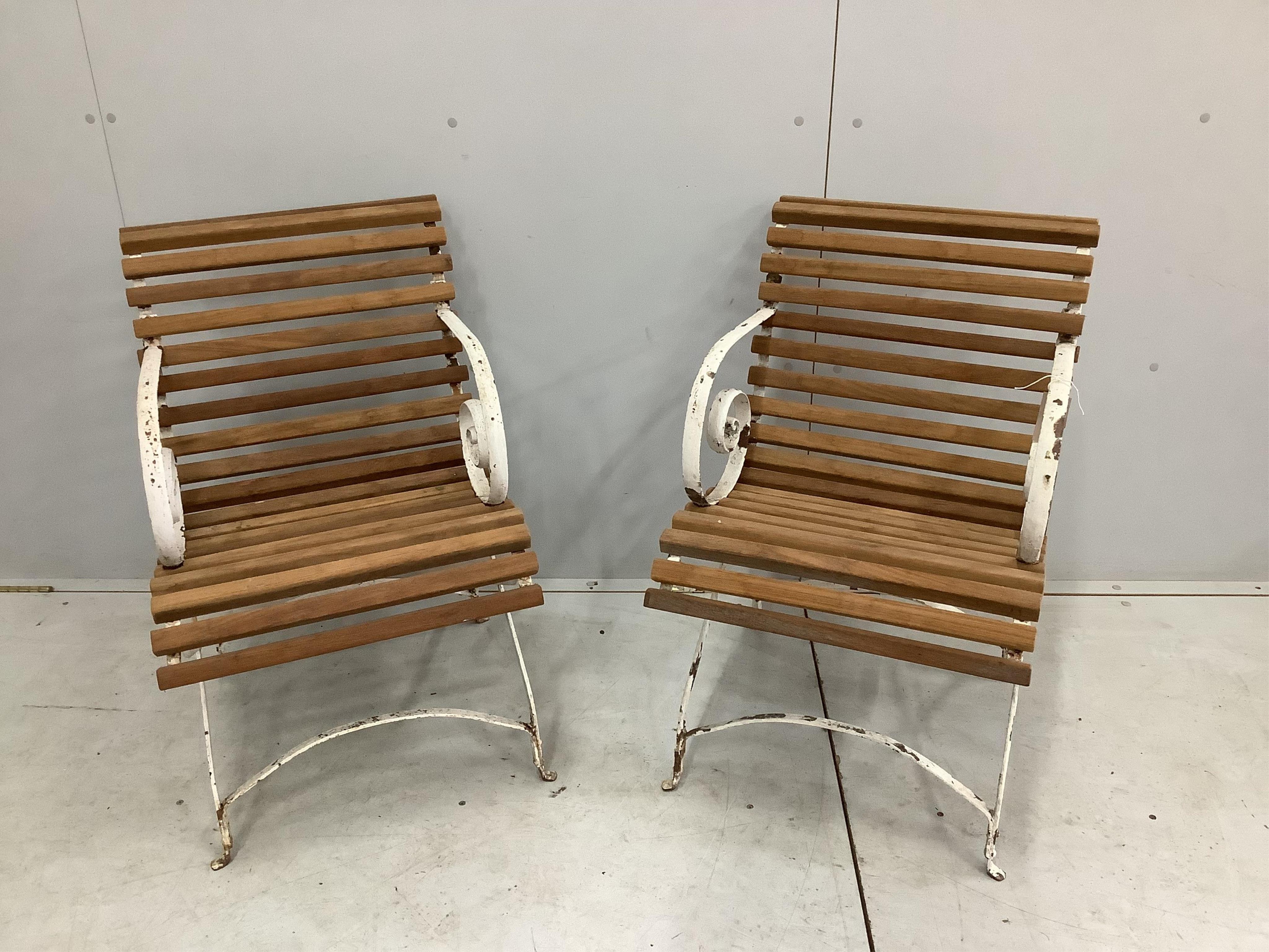 A pair of white painted wrought iron teak slatted garden elbow chairs, width 49cm, height 80cm. Condition - some paint loss, otherwise fair